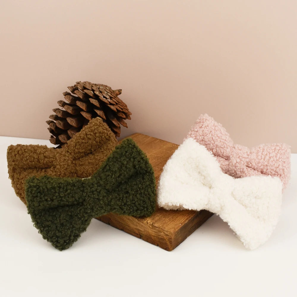 Plusieurs nœuds papillon détachables pour collier chien en tissu bouclette présentés sur un support en bois.