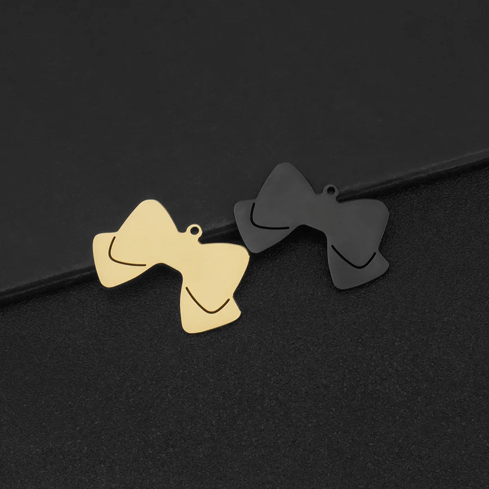Pendentif nœud papillon doré et pendentif noir sur fond sombre.