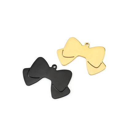 Deux pendentifs nœud papillon noir et doré sur fond clair.
