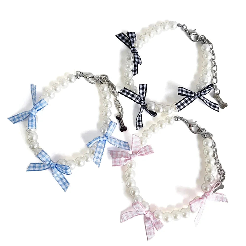 Collection de colliers fantaisie pour chiot en perles nacrées avec rubans à carreaux en trois coloris sur fond blanc.