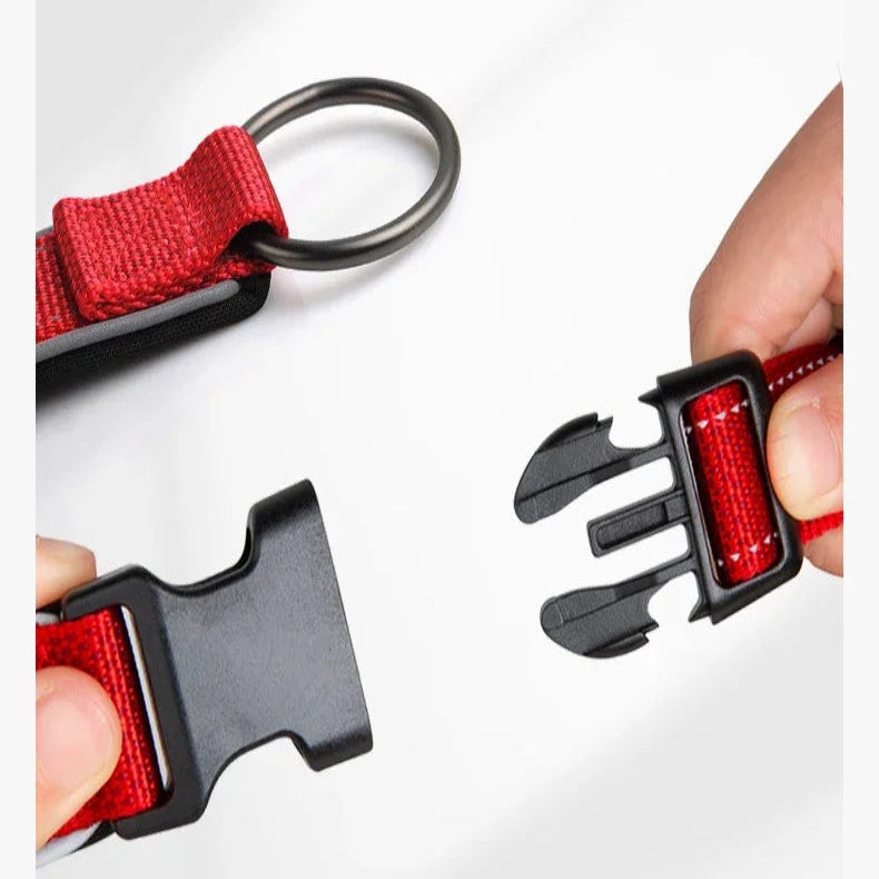 Zoom sur la boucle rapide du collier rouge en position d'ouverture avec mains manipulant le clip.