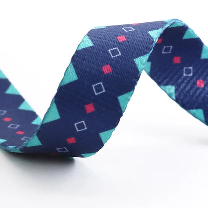 Zoom sur la sangle en nylon bleu marine montrant les motifs géométriques turquoise et roses sur fond blanc.